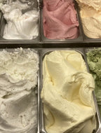 Scoops of assorted gelato colors—white, pink, yellow, green, and off-white—are displayed in metal containers, including the limited-edition Pear Gelato Body Oil with zinc and pearl extract by Summer Solace Tallow.