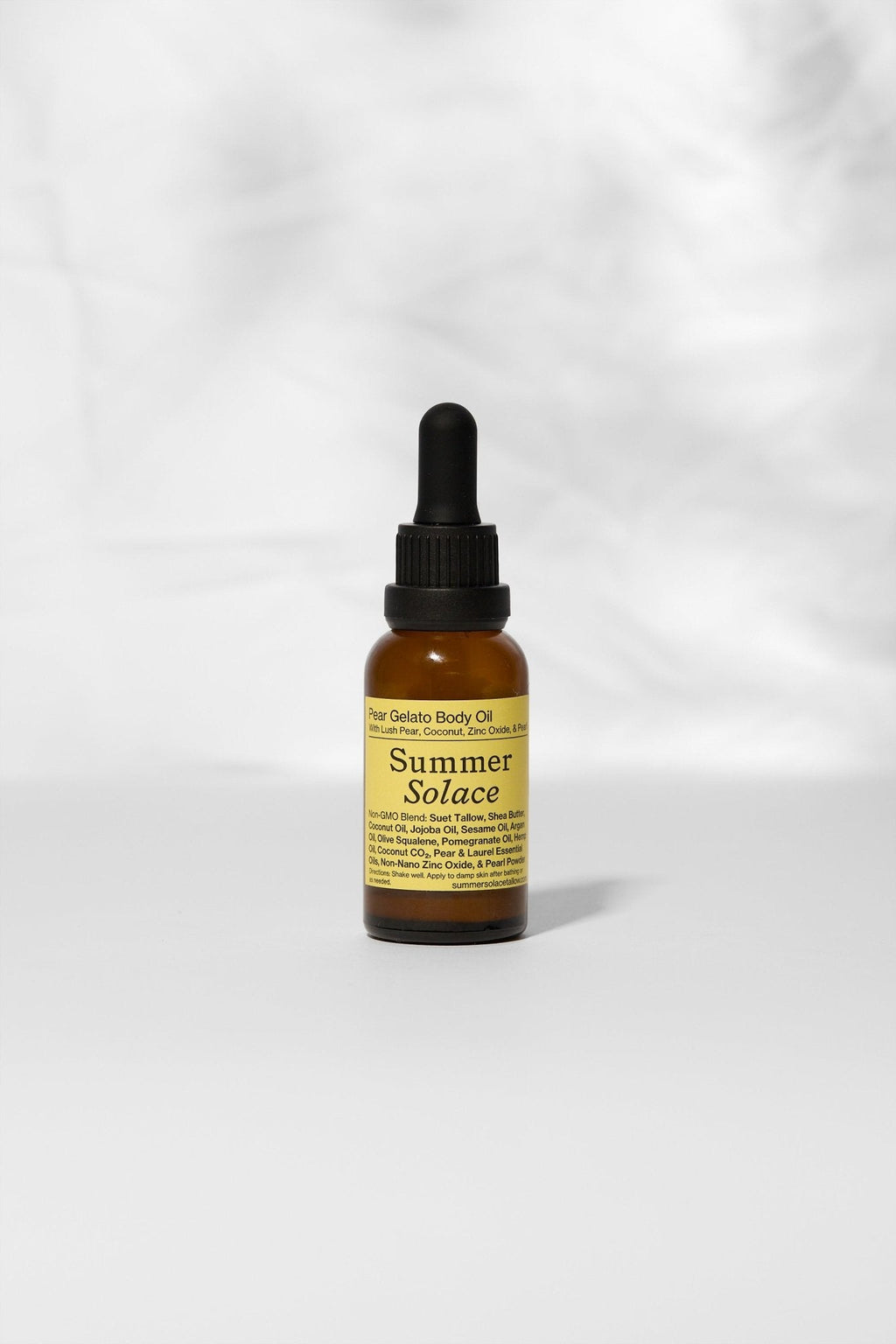 A small amber dropper bottle labeled "Pear Gelato Body Oil – Zinc and Pearl Extract (Limited Edition)" by Summer Solace Tallow, a skin-brightening oil, stands upright on a light gray surface before a soft, blurred white background.