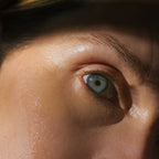Close-up of a blue eye and eyebrow, with smooth, dewy skin enhanced by Summer Solace Tallow’s Emanations Profound Face Oil—featuring tallow, emu oil, champa, tuberose & white ginger lily. Natural light highlights stunning detail.