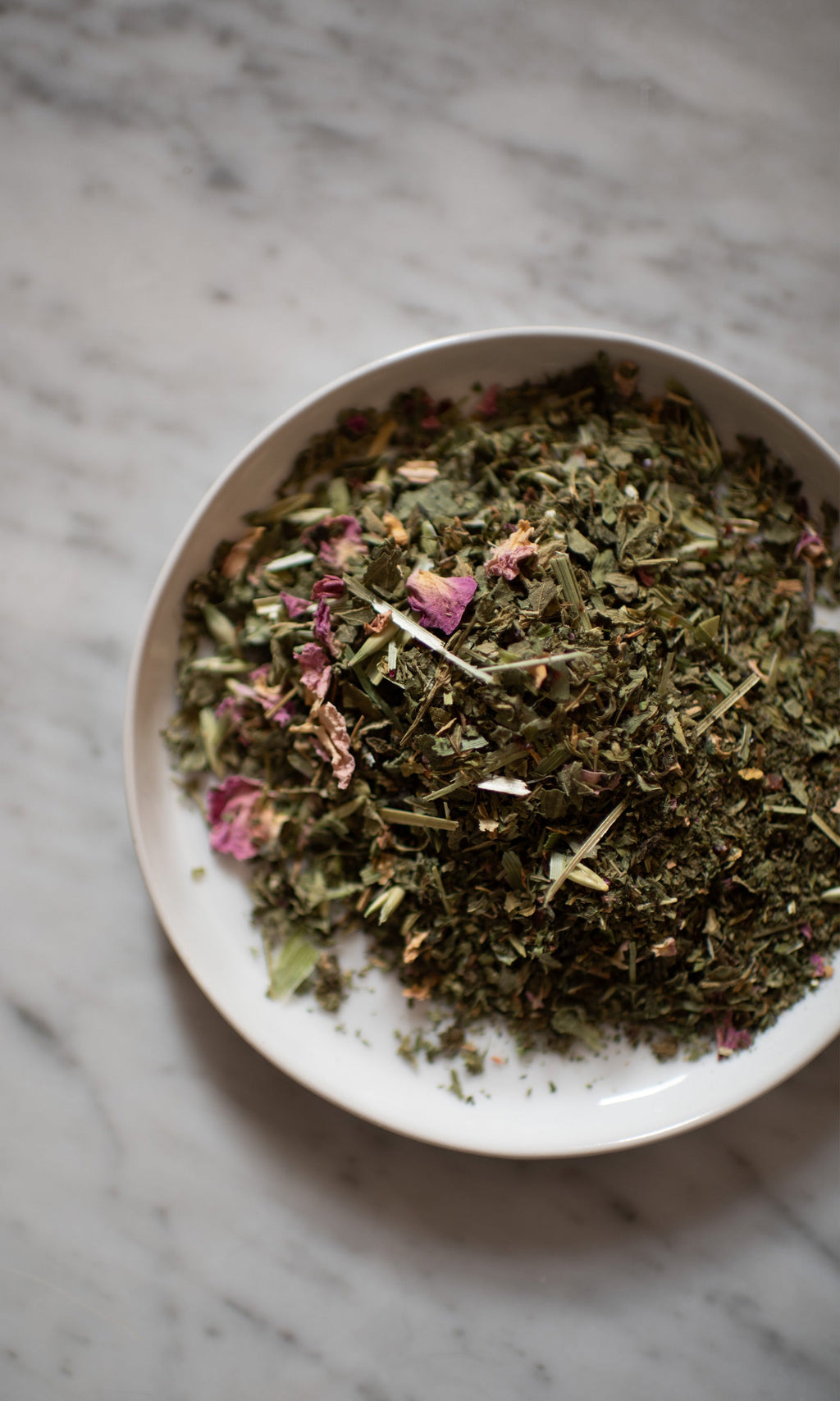 PLANTWALK FIELD | Everyday Minerals Herbal Infusion, a loose blend of dried herbs and flower petals for herbal mineral supplementation, rests on a light gray marble surface.