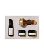 The Surya Skincare Discovery Set includes a serum bottle with pump, two small cream jars, and a Kansa Wand massage tool, all neatly arranged in a beige box.
