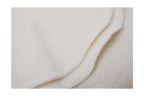 A close-up of the edge of Shepherd’s Dream Organic Merino Wool Blanket shows its soft, cream-colored fabric and detailed hem stitching.