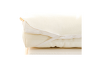 A close-up of the Baile Wool Mattress Protector, cream-colored and washable with elastic straps, folded neatly atop a light foam mattress.