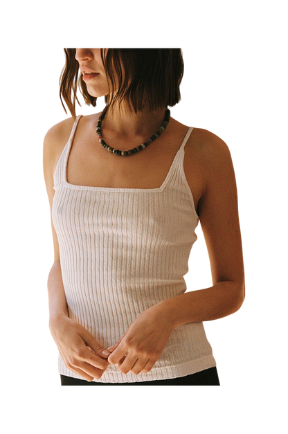 A woman with chin-length brown hair wears the LA Relaxed Pointelle Square Cami and a beaded necklace, standing against a plain background with her hands loosely clasped in front of her.