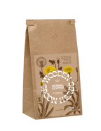 A brown paper bag labeled "WOODED SPOON HERBS" containing "Herbal Coffee," a caffeine-free blend featuring adaptogenic herbs, ashwagandha, and adaptogenic mushrooms. The front displays illustrations of yellow dandelions and other herbs. The bag has a folded top closure.