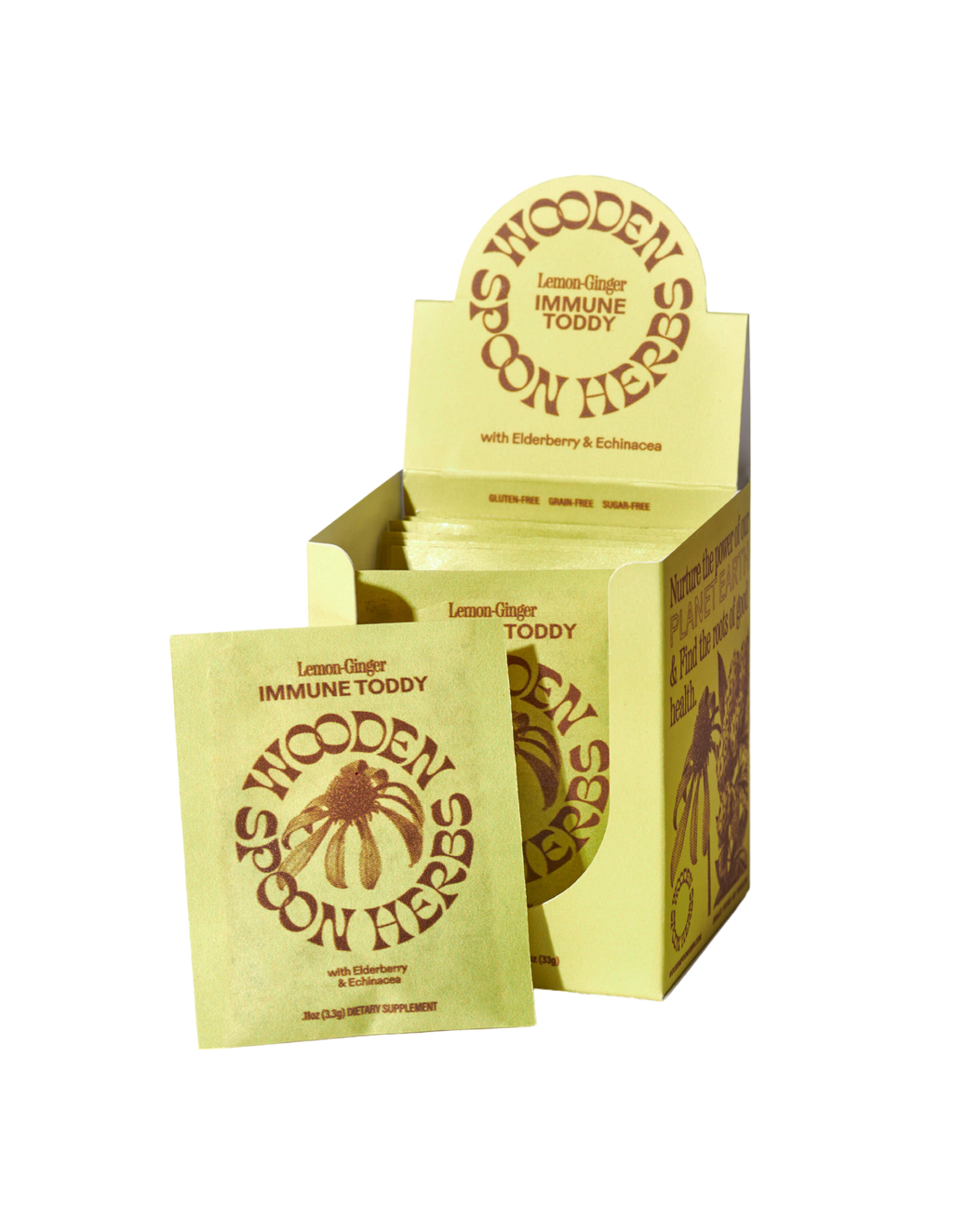 A yellow box labeled "WOODEN SPOON HERBS Lemon-Ginger Immune Toddy" with a supplement packet leaning against it. Both feature brown text, a flower illustration, and highlight echinacea for immune support.